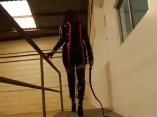 Mistress in high heels readies her whip for BDSM slave